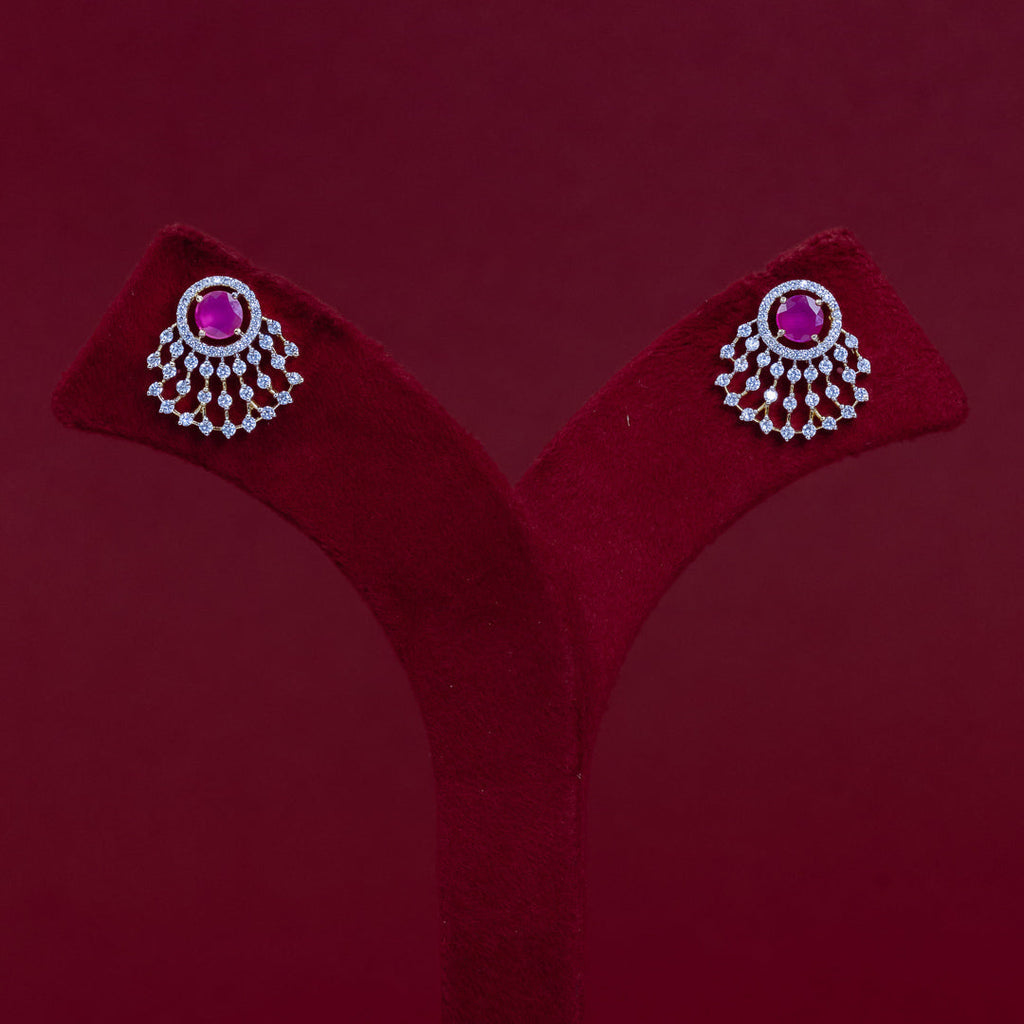 A pair of silver-toned statement earrings with round pink gemstones and dangling crystal-like accents, displayed on a red velvet jewelry stand against a dark red background.